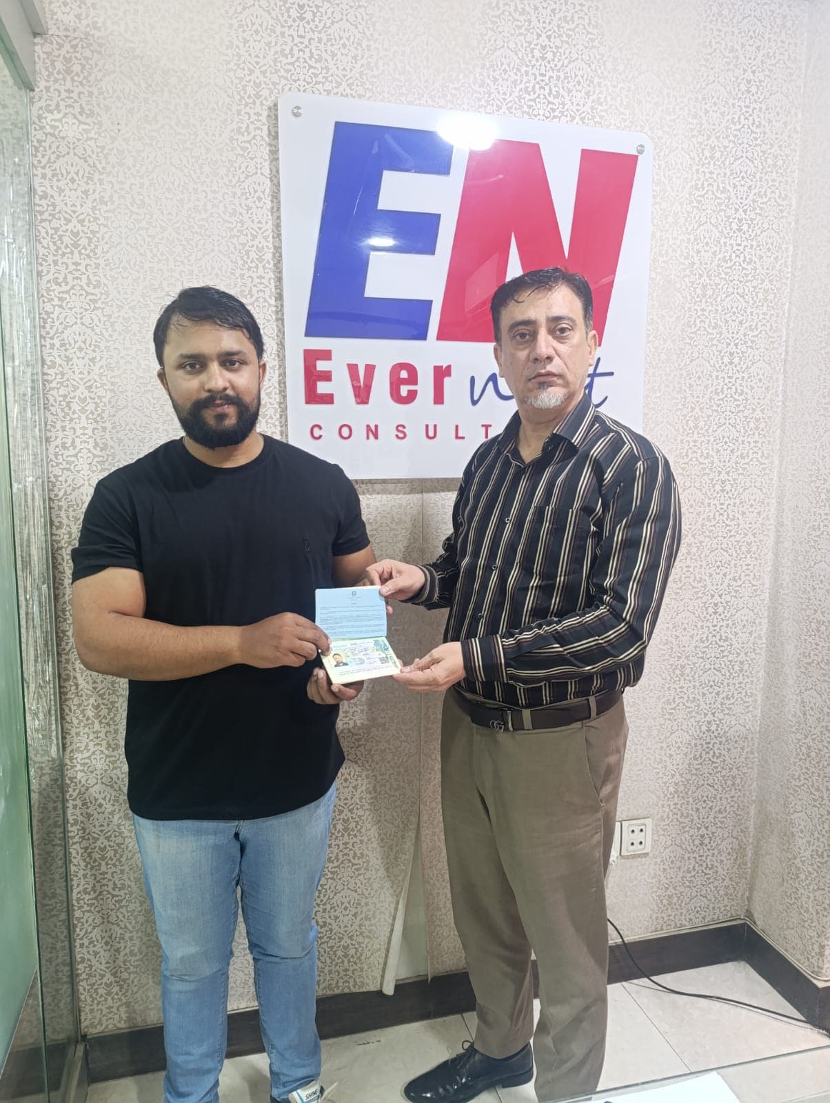 Ahsan Nazir in a black shirt with Sir Raza holding his Italian student visa