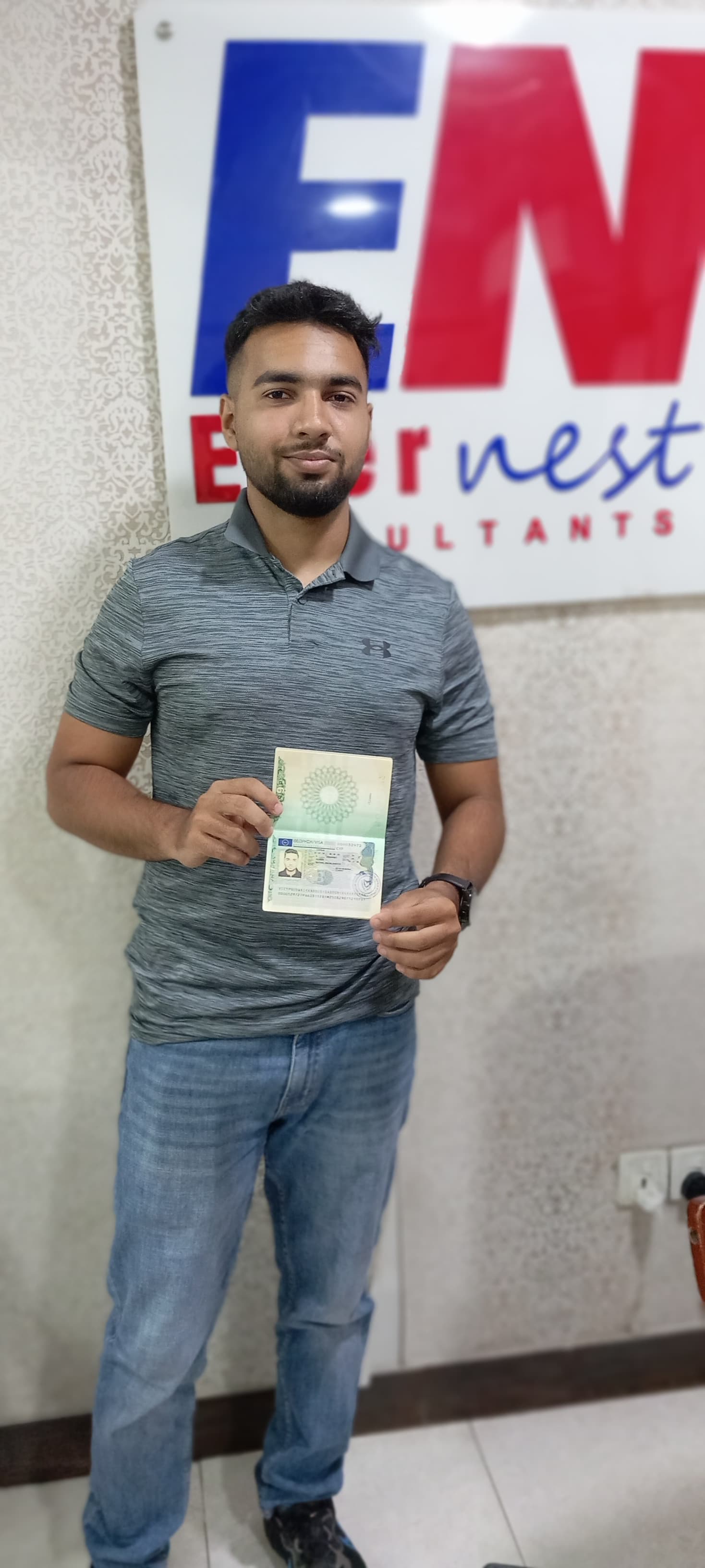Saboor Quadwai holding his visa with Evernest branding in the background